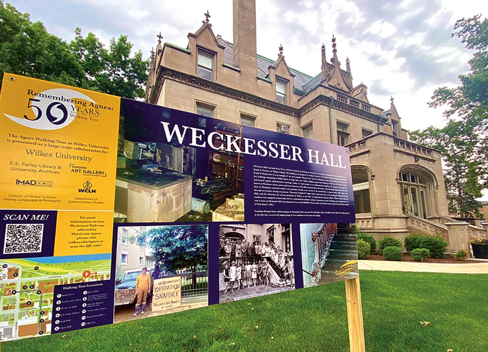 Outside Weckesser Hall with large sign “Remembering Agnes: 50 Years Later,” a walking tour