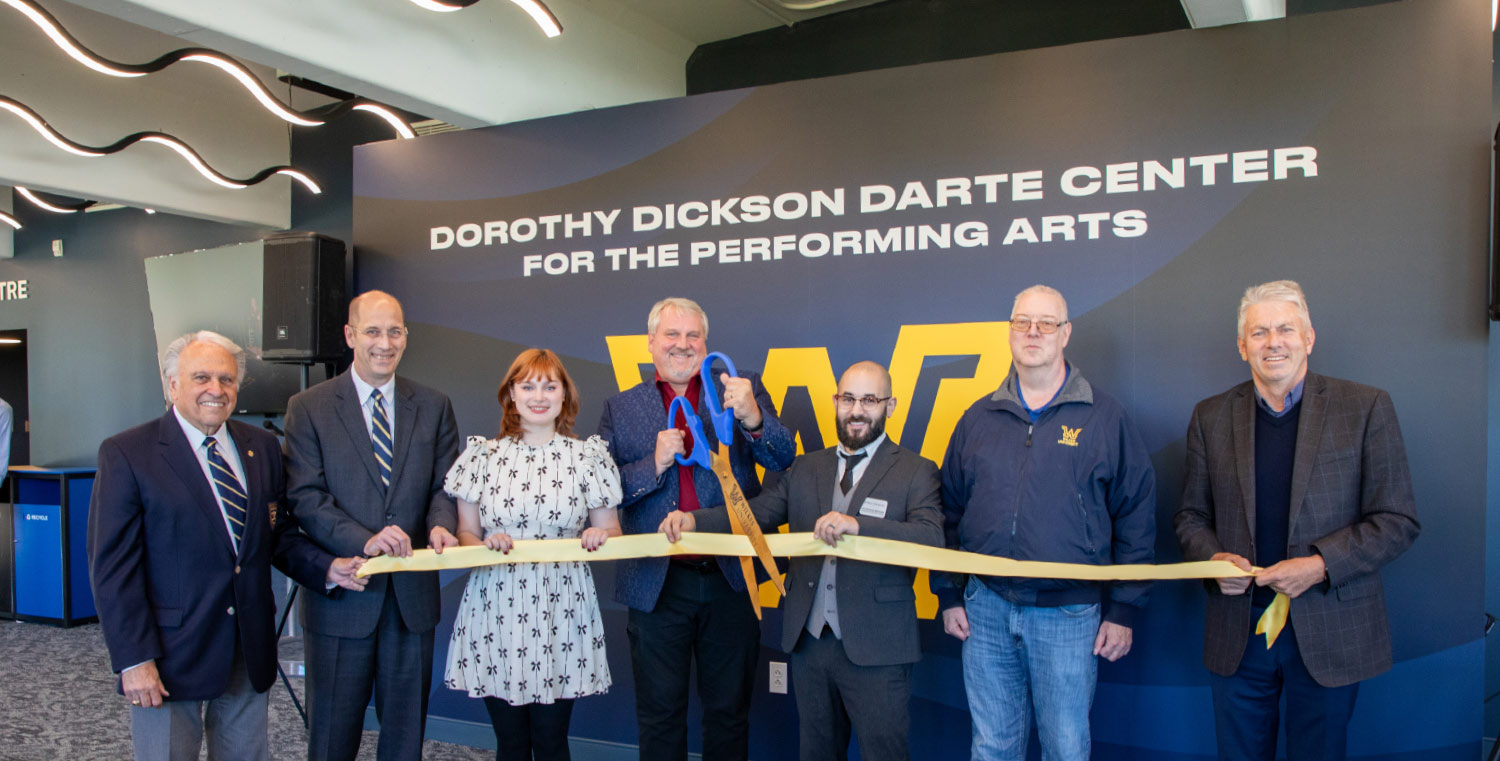Ribbon-cutting ceremony at the Dorothy Dickson Darte Center for the Performing Arts with seven people holding large blue and gold scissors.