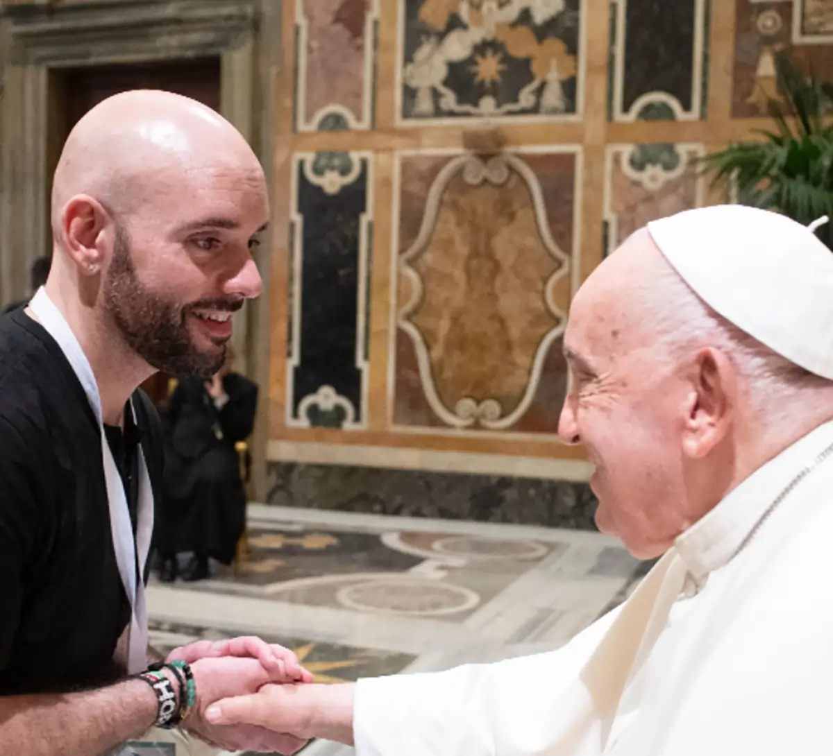 Mark Congdon Jr., PhD, smiling as he shakes his right hand with Pope Francis inside a Vatican City building