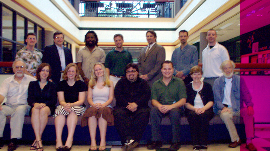 a group of graduates take a photo with some standing and others sitting in an in door setting