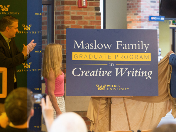 cropped view of the unveiling of signage that reads “Maslow Family Graduate Program in Creative Writing” during an indoor event